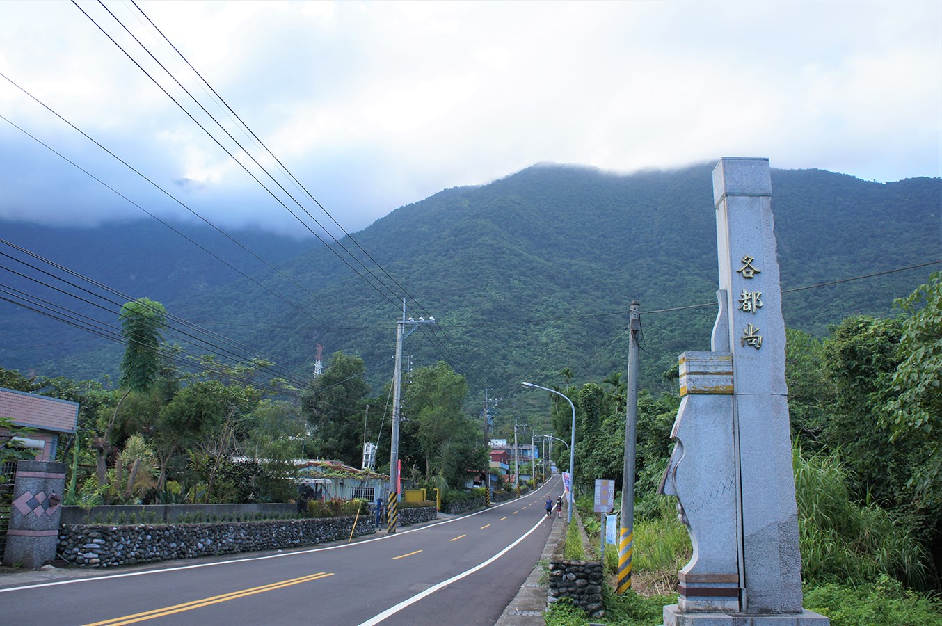 佳民格督尚部落入口,石柱題有各都尚,旁有道路與山景