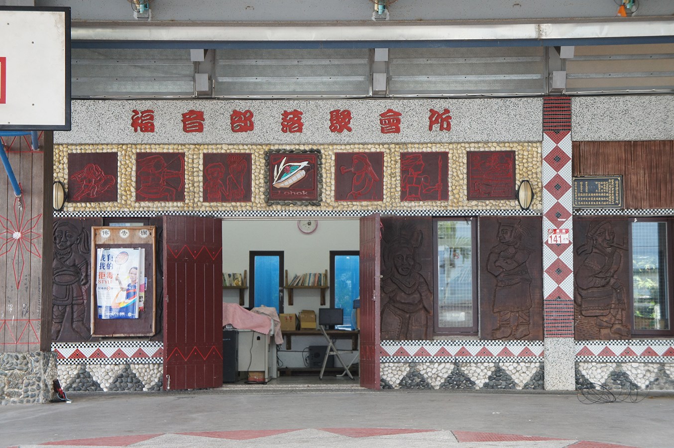 洛合谷部落聚會所正面,建物可見福音部落聚會所字樣、Lohok圖案與人物浮雕